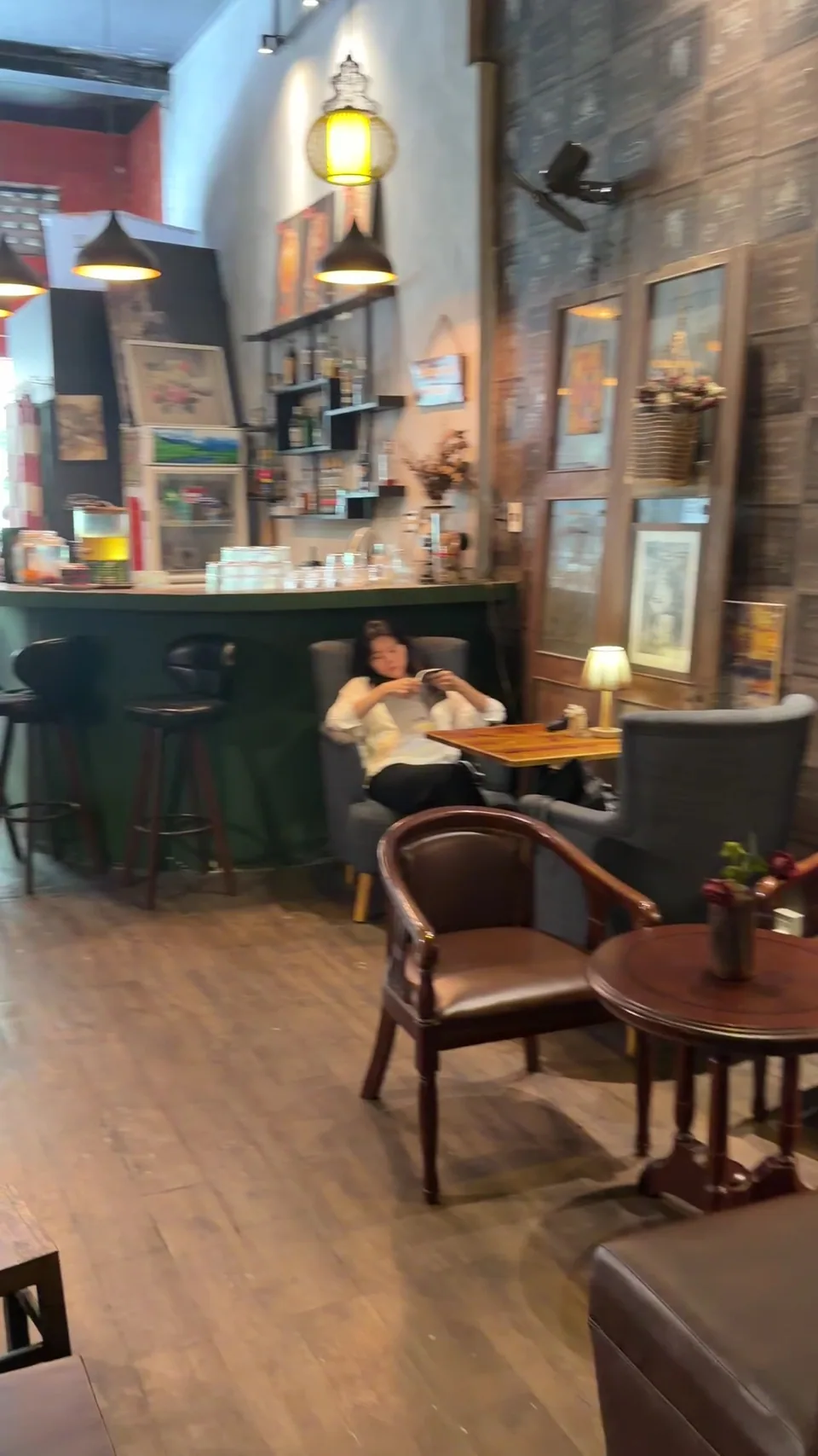Bên trong Whisfee Café với quầy bar xanh, ghế bành và đèn vàng
